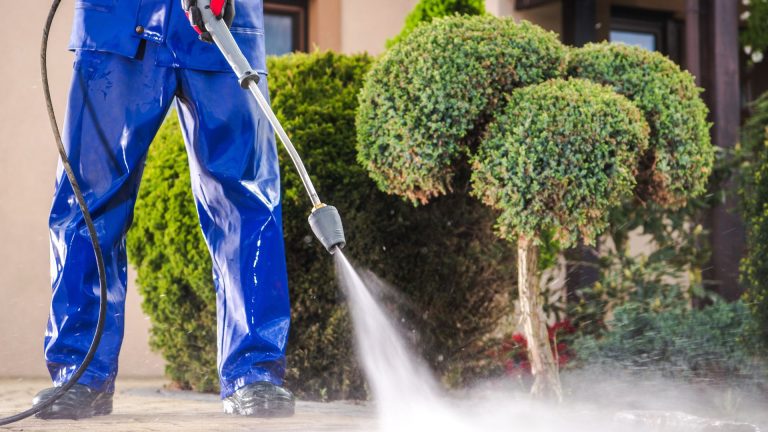 Person pressure washing outdoor surface