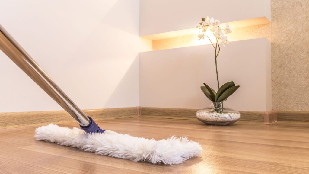 Cleaning wooden floor with mop and orchid decoration