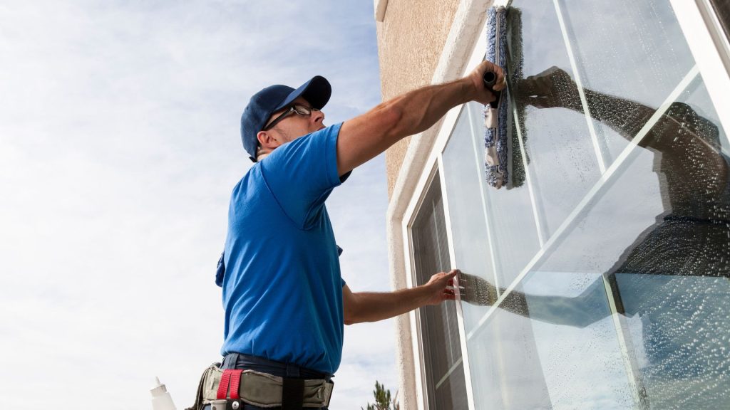 Window cleaner working on tall building window.