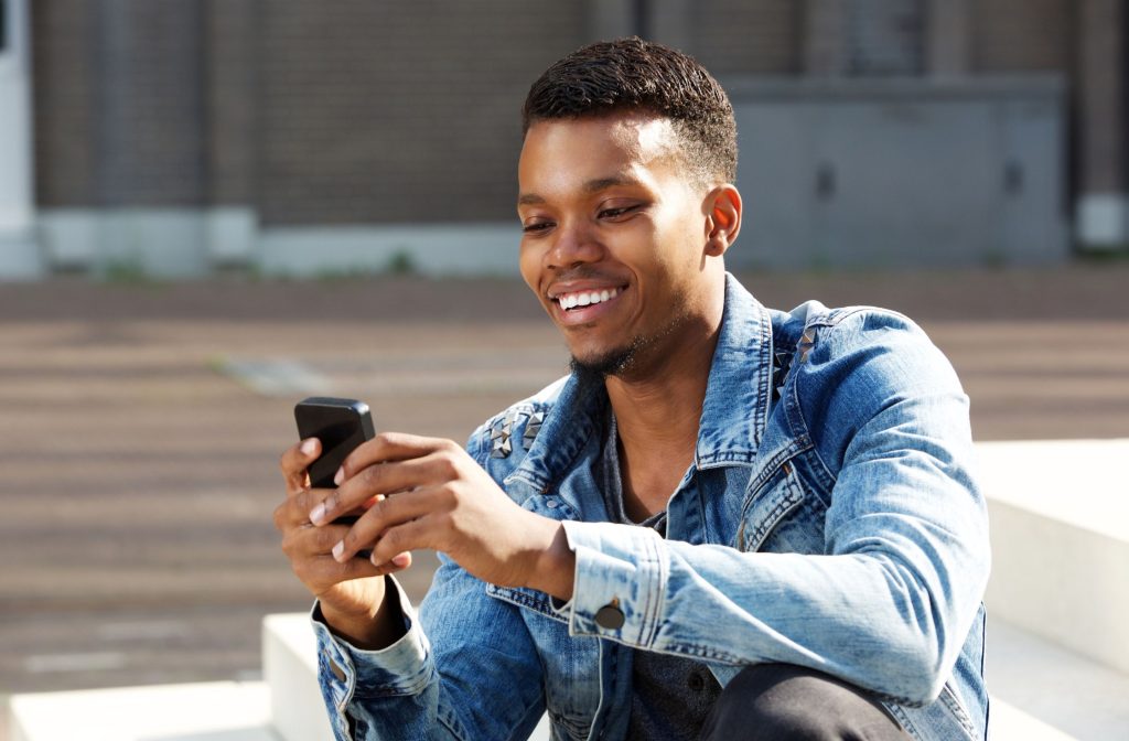 Smiling person using smartphone outdoors.