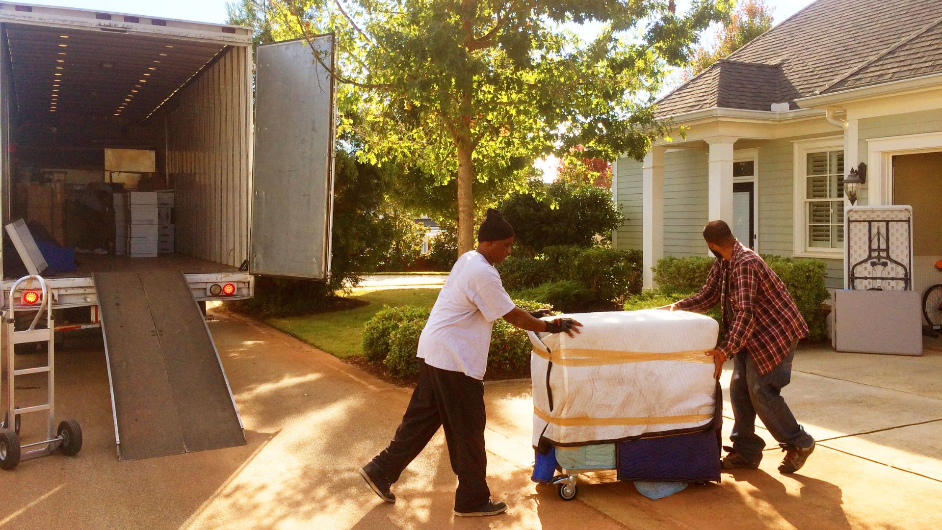 Workers loading moving truck on a sunny day.